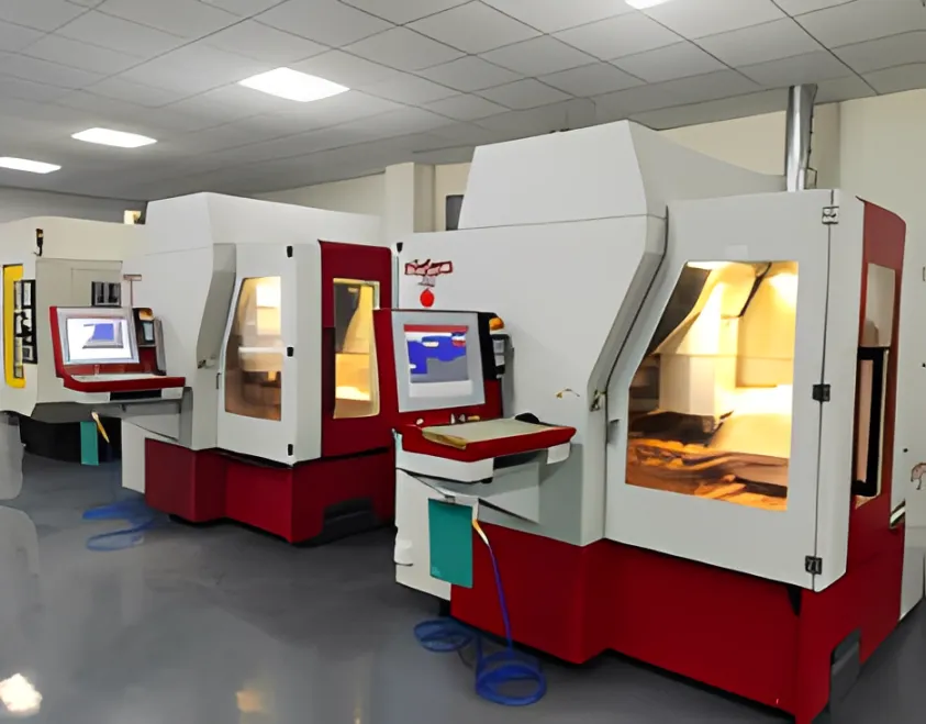 A row of red and white machining centers with control screens.