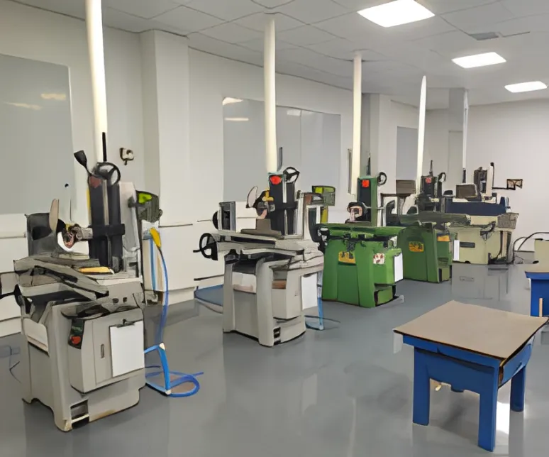 A workshop floor with milling machines, workbenches, and blue stools.
